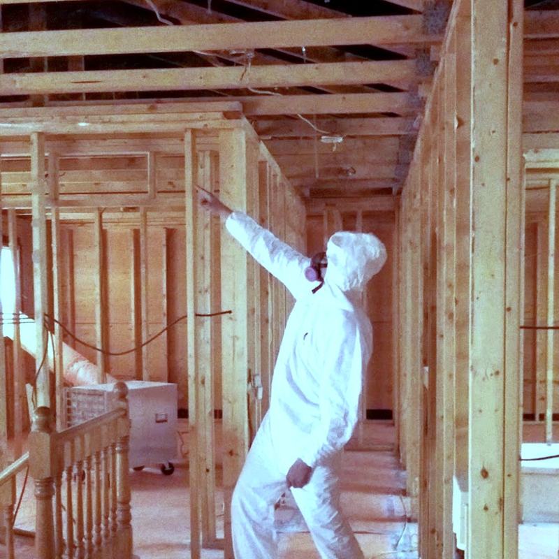 Aden Integrated Services worker in full PPE beside a negative air unit inside an asbestos containment